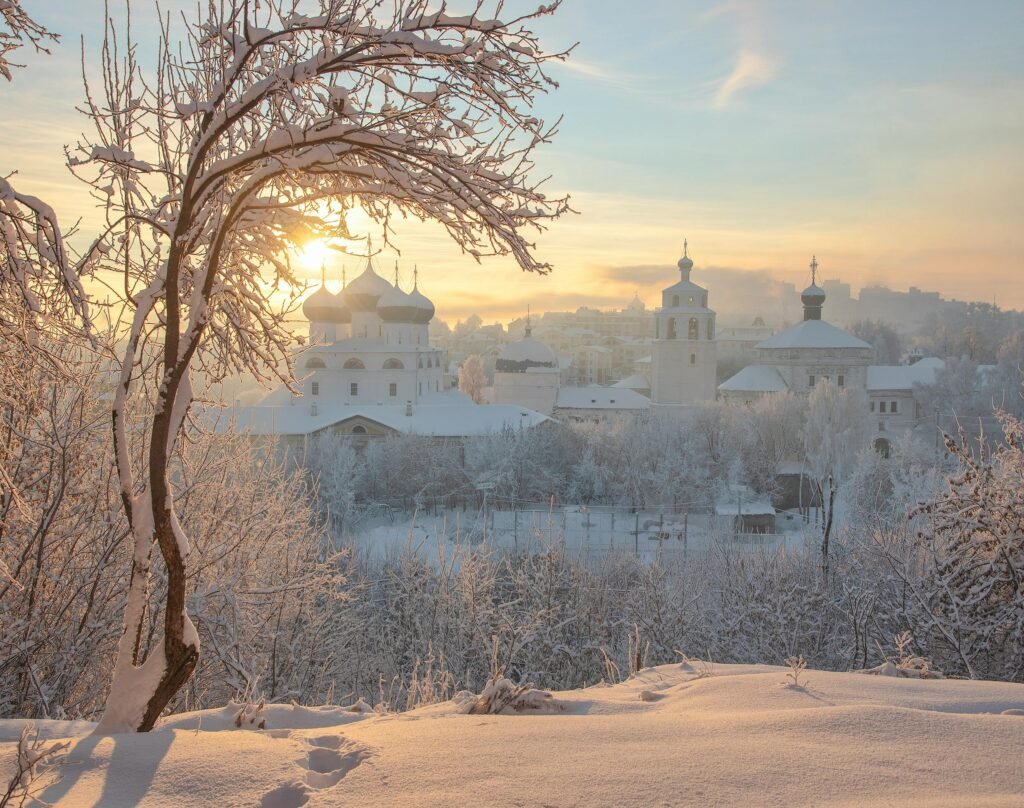 10 itens essenciais para sua mala de inverno no leste europeu: não viaje sem estes! Beautiful winter scene with snow-covered church and trees at sunrise, capturing serene and tranquil atmosphere.