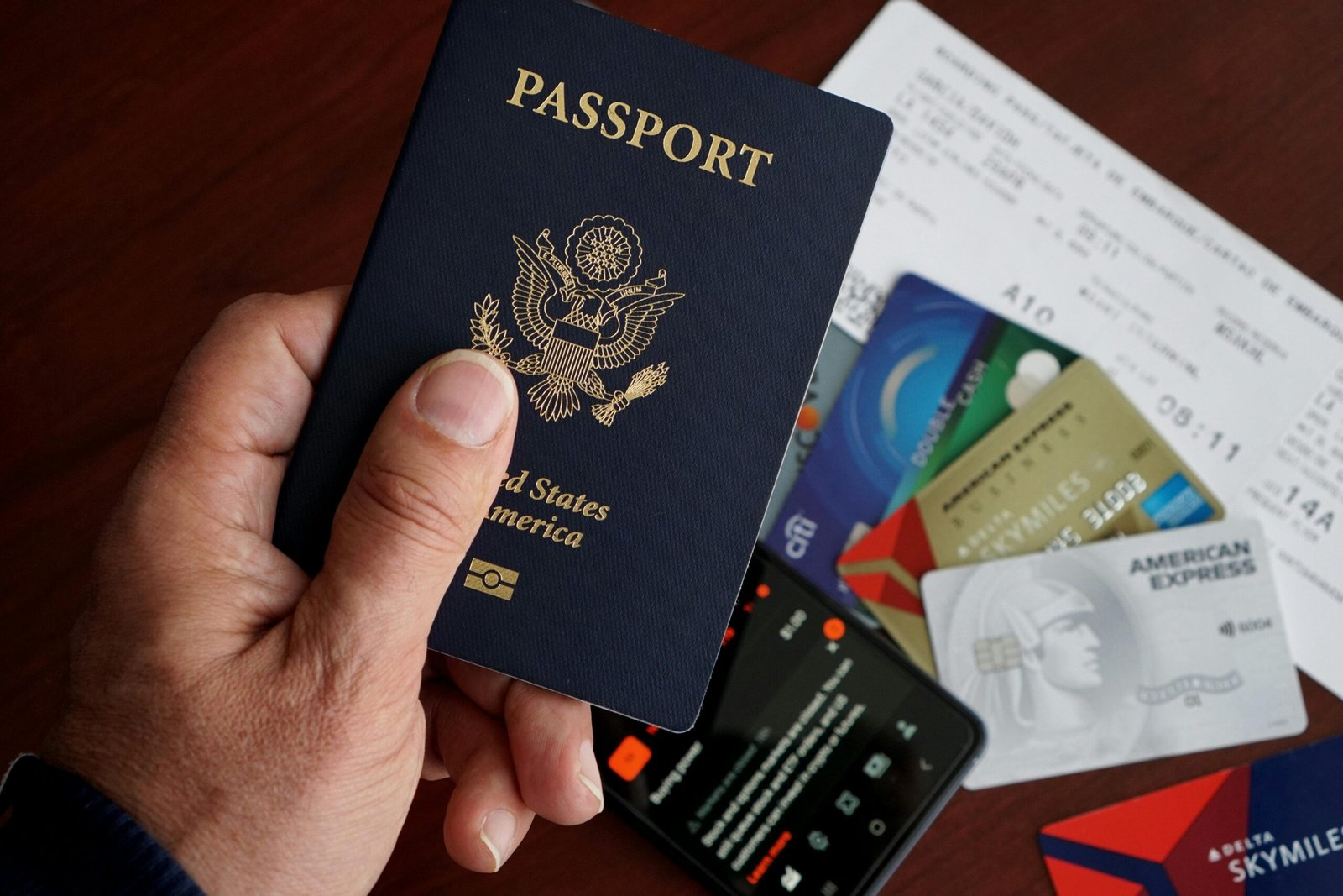 Home A close-up of a US passport with credit cards, tickets, and a mobile phone on a table.
