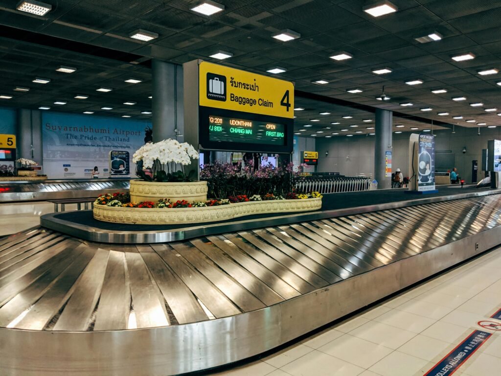 Airtag: O Item de Segurança Obrigatório para Sua Mala em 2026 Modern baggage claim area at Suvarnabhumi Airport in Bangkok with luggage carousel and signage.